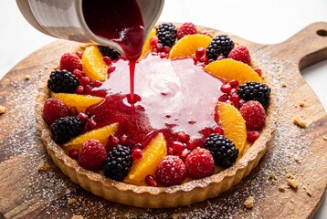 Garnished Fruit Tart with Red Berry Sauce Being Poured