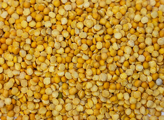 Close-up texture of dry yellow split peas filling the entire frame. Detailed ingredient photo ideal for packaging, product listings, recipes and healthy nutrition content.
