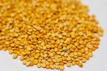 Pile of dry yellow split peas on a white background. Clean food ingredient photo suitable for packaging, product listings, recipes and healthy nutrition content.