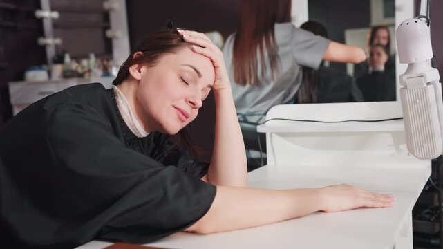 podcaster at salon, stylist background postrecording, reflective posture after microphone session, stylists in background observing drained podcaster during recording session break