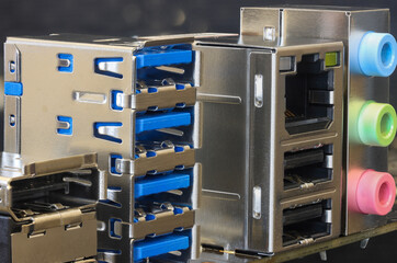 Close-up of a metal back panel featuring stacked USB ports, RJ 45 and color coded audio jacks