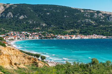 Obraz premium Scenic coastal town with turquoise waters and rugged hills. Baška, Krk island, Croatia