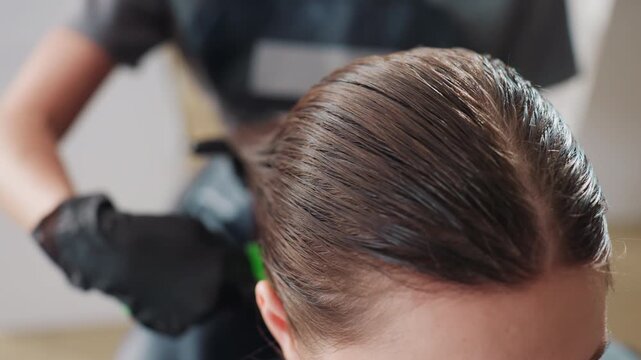 stylish hair smoothing, closeup of hair treatment, brown hair being carefully styled by professional stylist, closeup image capturing stylist smoothing hairline with green brush in salon