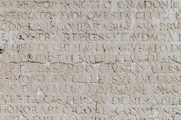 Ancient latin inscription on weathered stone wall