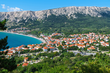 Coastal town with orange roofs by the sea and mountainous backdrop. Ba&scaron;ka, Krk island, Croatia