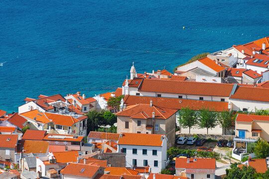 Aerial view of coastal town with red-tiled roofs by blue sea. Baška, Krk island, Croatia