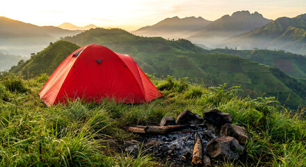 A vibrant red camping tent stands on a grassy mountain ridge at sunrise, with misty hills and layered terraces stretching into the distance.