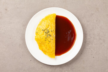 밥을 고기나 야채 따위와 함께 볶고 그 위에 달걀을 얇게 부쳐서 씌운 요리.
A dish made by stir-frying rice with meat or vegetables and topping it with a thin layer of fried egg.

