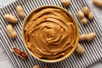 Fototapeta premium Creamy Brown Peanut Butter in a Bowl, top view. Close-up.