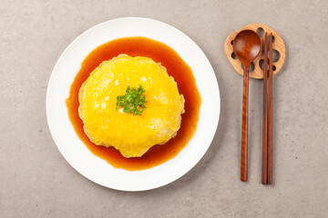 밥을 고기나 야채 따위와 함께 볶고 그 위에 달걀을 얇게 부쳐서 씌운 요리.
A dish made by stir-frying rice with meat or vegetables and topping it with a thin layer of fried egg.

