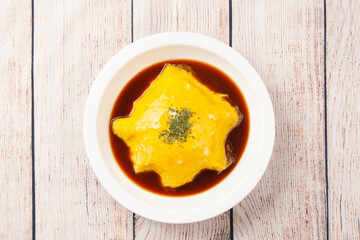 밥을 고기나 야채 따위와 함께 볶고 그 위에 달걀을 얇게 부쳐서 씌운 요리.
A dish made by stir-frying rice with meat or vegetables and topping it with a thin layer of fried egg.

