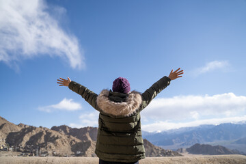 Traveler raising arms enjoying mountain view in Leh, Ladakh