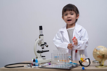Curious child in a lab coat exploring science with microscope and colorful lab equipment, representing early STEM education, creativity, innovation, and learning in a playful classroom environment.