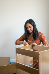 A woman is working on a wooden box, possibly assembling it