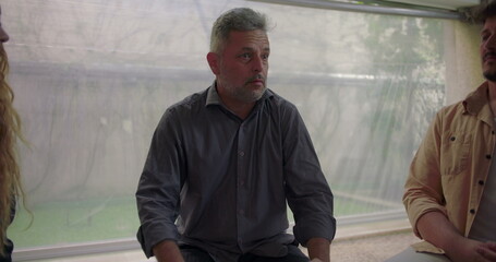 Fototapeta premium Man revealing personal struggle in emotional group therapy session, speaking with urgency and vulnerability as participants listen with empathy in safe healing space