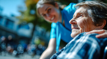 Smiling elderly woman in a wheelchair enjoying a sunny outdoor walk with a supportive nurse