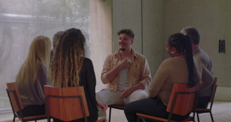 Man sharing emotionally in group therapy, using expressive gestures to communicate truth and...