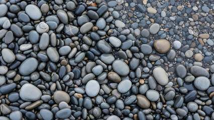 Seamless background of naturally tumbled wet stones and smooth gray beach pebbles in clear water