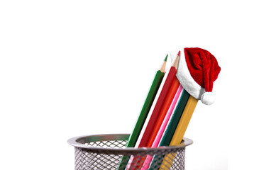 Santa Claus Hat on colour pencils in holder on white background with copy space. Christmas and New Year holidays