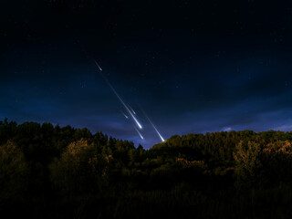 Meteors illuminated the evening sky. Bright meteor trail over the hill. Astronomical observation of shooting stars. © Nazarii