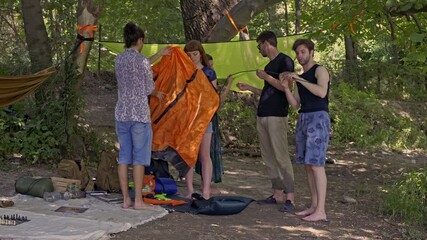 Young friends collaboratively set up their tent in a lush green forest. This outdoor adventure highlights teamwork and shared experiences during a memorable camping trip. - Powered by Adobe