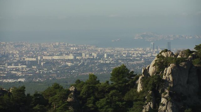 Vue de Marseille depuis le massif de l’Étoile, vue aérienne en mouvement avec les arbres et la roche au premier plan 