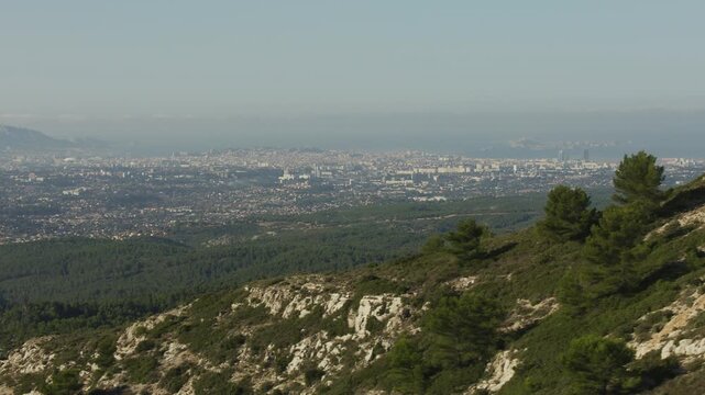 Vue de Marseille depuis le massif de l&rsquo;&Eacute;toile, vue a&eacute;rienne en mouvement avec les arbres et la roche au premier plan 