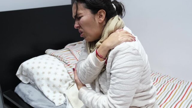 Young woman in bed suffering from sudden, intense shoulder and arm pain, possibly fibromyalgia
