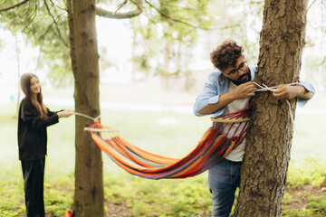 Couple setting up colorful hammock in park