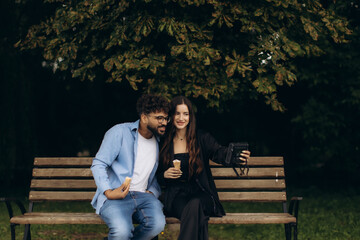 Diverse couple recording vlog with ice cream in park