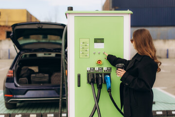 Woman charging electric vehicle at green station