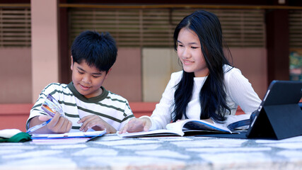 Asian Students Studying Together Outdoors with Books and Tablet