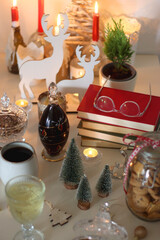 Cookie jar, tea, wine, nuts, books, lit candles and Christmas decorations on the table. Cozy Christmas hygge at home. Selective focus.