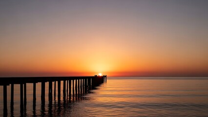 Wooden Pier Silhouetted Against a Vibrant Orange Sunset Over a Calm Ocean jetty dock