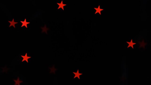 Red stars flicker randomly against a deep black background, creating a simple, abstract, and dynamic visual effect.