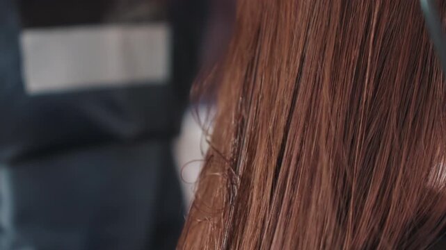 green brush enhances shiny finish, salon scene with stylist brushing hair for sleek shine, professional stylist uses green paddle brush to glide through long brown hair for polished finish