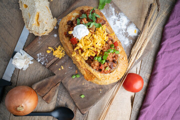 Chilli topped with green onions, freshly shredded cheddar cheese, cilantro, and a dollop of sour...