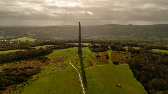 Obelisk monument casting long shadow over green landscape