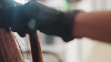 closeup of hairstyling action, bright salon environment with focused hair styling activities captured, detailed shot of hairdresser carefully separating strands using round brush and glove