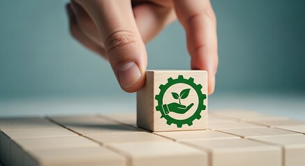 Sustainable industry and eco friendly manufacturing hand placing a wooden block with green gear and plant icon on a stack of blocks