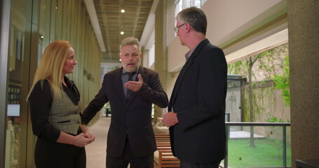 Manager introducing colleagues to one another in office hallway, professional team members exchanging greetings in corporate environment © Marco