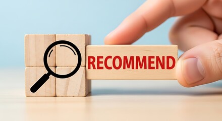 Hand placing wooden block with the word recommend next to a block with a magnifying glass suggesting a search or endorsement concept