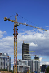 Fototapeta premium Construction cranes and new buildings, construction work of modern skyscrapers on a sunny day.