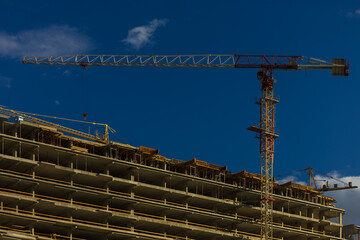 Naklejka premium Construction cranes and new buildings, construction work of modern skyscrapers on a sunny day.