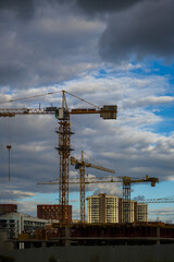 Fototapeta premium Construction cranes and new buildings, construction work of modern skyscrapers on a sunny day.