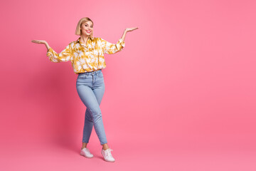 Young woman in casual yellow shirt and jeans poses happily against pink background for fashion lifestyle stock image