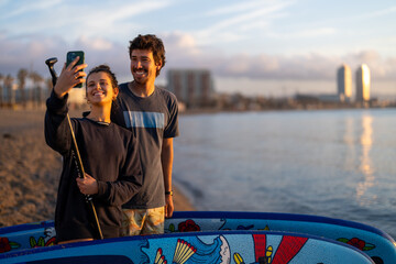 Coastal sunset frames couple enjoying a relaxed moment together as they take a cheerful selfie