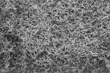 Full-frame close-up macro texture of a dark grey, non-woven abrasive material. The surface is dense, rough, and fibrous. Concept for cleaning, industrial background, abstract pattern, and grunge.