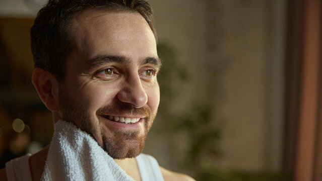 Smiling man drying face with towel after morning wash. Concept of skincare advertising, wellness content, men grooming routines, healthy complexion visuals, clean lifestyle aesthetics.