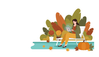 Relaxed woman using tablet outdoors in autumn garden with pumpkin and fall foliage